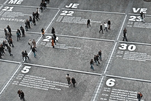 personas caminando entre los dias y horas marcados en el suelo como un calendario