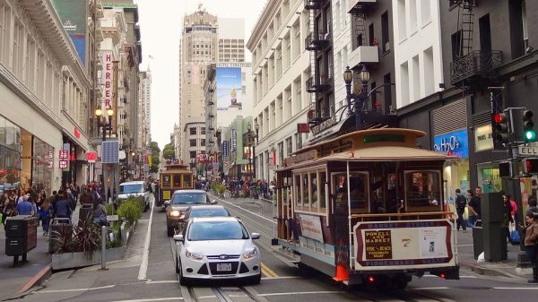  Image of a street in San Francisco where both cars and a tram circulate